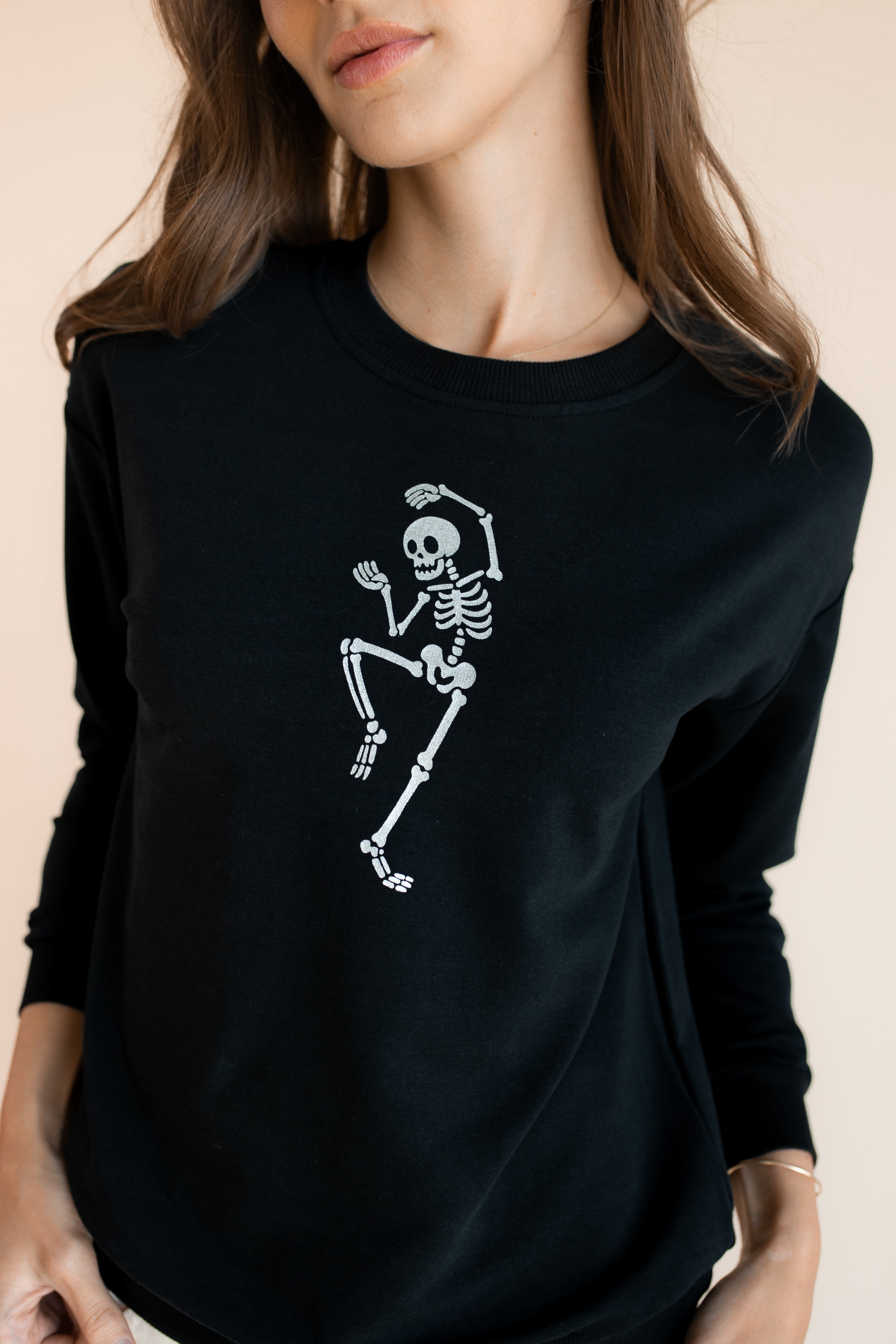Close up of Modal wearing Black Women's Sweatshirt with Skeleton print in the center on a beige background