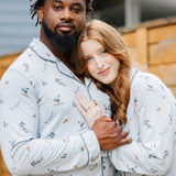 Couple standing side by side with female resting her head and hand in partners chest. Both matching in Men's and women's Long Sleeve Pajama Set in Ski