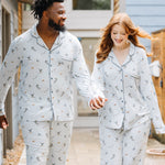 Smiling couple walking down a sidewalk wearing matching Men's and Long-Sleeved Women's Pajama Set in Ski
