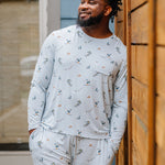 Smiling male model wearing the Men's Jogger Set in Ski looking off to the side leaning up against a fence 