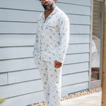 Male model standing in front of a house wearing the Men's Long Sleeve Pajama Set in Ski with one hand in the pants pocket