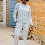 Smiling model standing beside a wooden fence wearing the Women's Jogger Pajama Set in Ski