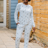 Smiling model standing beside a wooden fence wearing the Women's Jogger Pajama Set in Ski