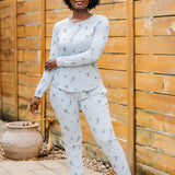 Smiling model wearing the Women's Jogger Pajama Set in Ski standing beside a wooden fence