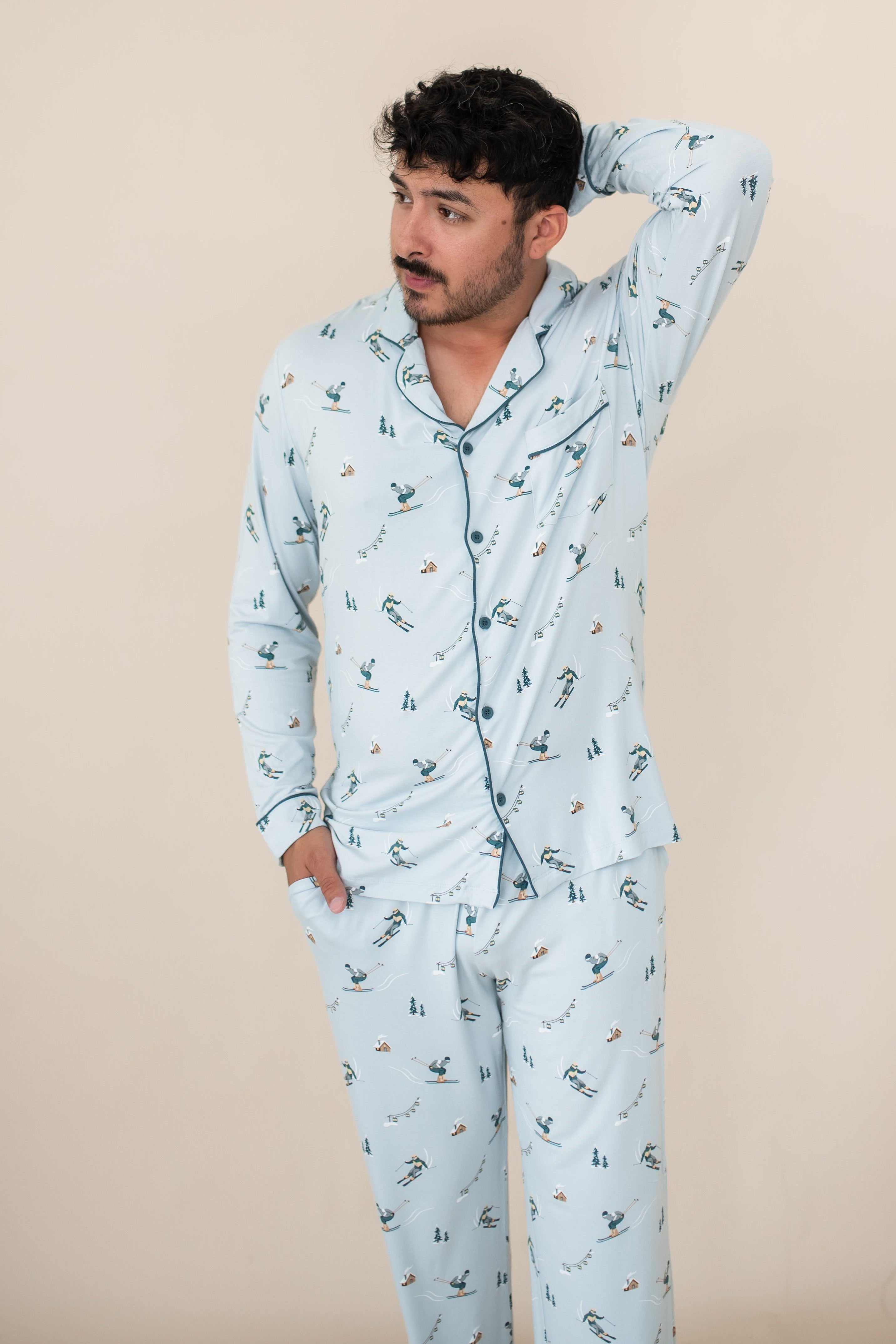 Male modeling the Men's Long Sleeve Pajama Set in Ski with one hand in the pants pocket and the other up behind is head