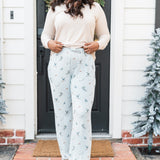 Female standing at a front door wearing the Women's Lounge Pants in Ski with a cream colored shirt and atlantic beanie