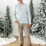 Smiling male modeling the Men's Long Sleeve Henley Top in Ski with khaki colored pants and light brown boots standing between frosted trees