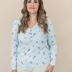 Female model wearing the Women's Long Sleeve Henley Tee in Ski with light beige pants standing in front of a light neutral background