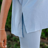 Person wearing light blue shorts with a blurred green background