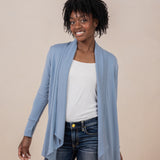 Female model wearing the Women's French Terry Wrap Top in Slate with a white top and dark wash jeans