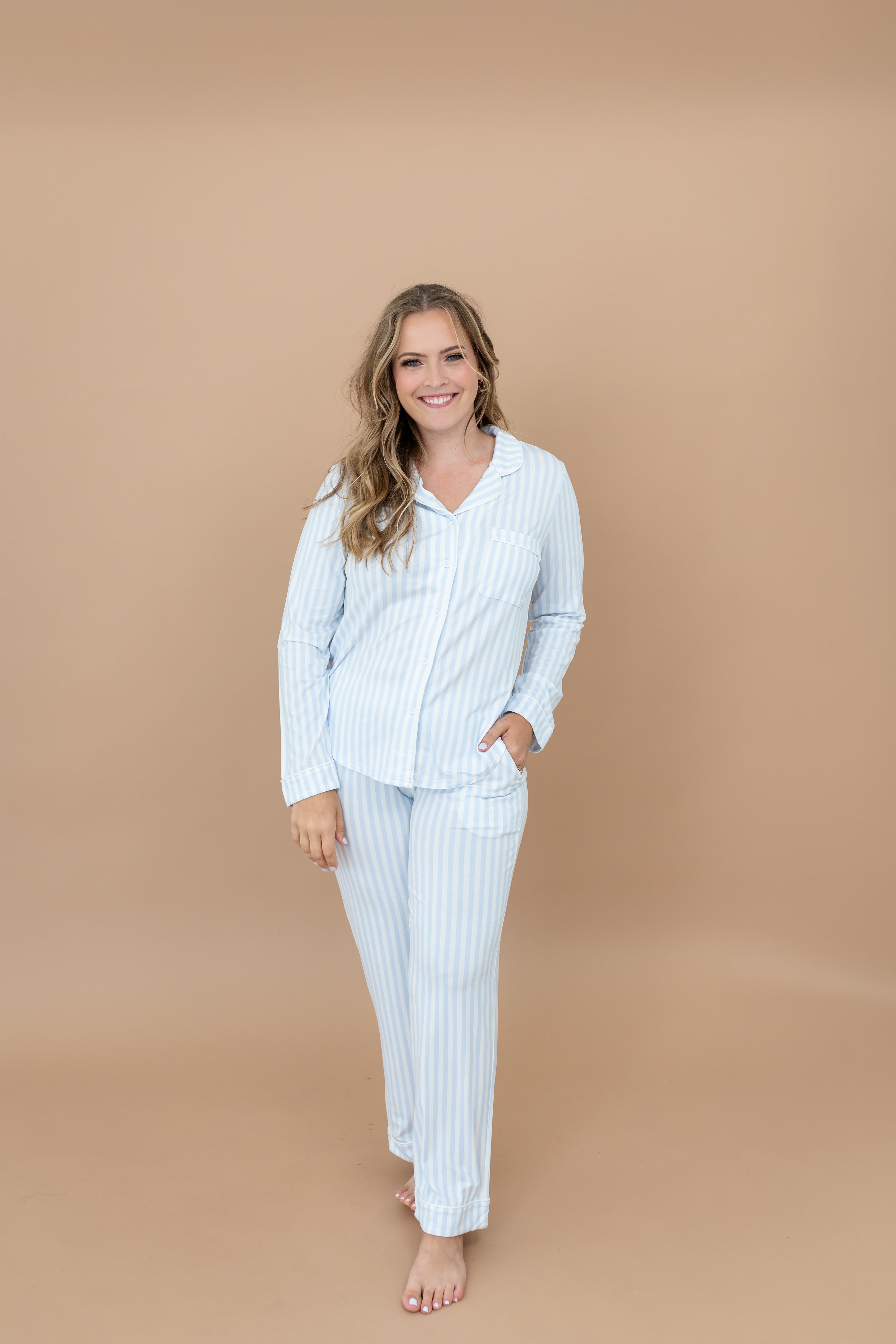 Close up of smiling model wearing the Long-Sleeved Women's Pajama Set in Small Mist Stripe with one hand in pants pocket