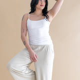 Woman wearing a white tank top and beige pants against a beige background ::: Model is 5'6" wearing size M ///