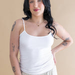 Woman wearing a white tank top and beige pants against a beige background ::: Model is 5'6" wearing size M ///