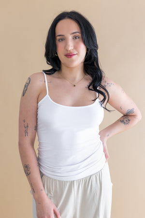 Woman wearing a white tank top and beige pants against a beige background ::: Model is 5'6" wearing size M ///