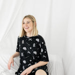 Smiling female sitting in a white blanket wearing the Women’s Biker Short Set in STAR WARS™