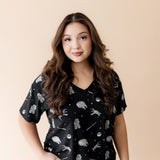 Female modeling the Women's Relaxed Fit V-Neck in STAR WARS™ paired with white pants