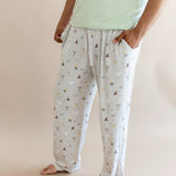 Person wearing cream men's lounge pant with pockets having Harry Potter prints with green shirt on a beige background