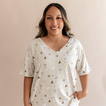 Smiling woman modeling the Women's Relaxed Fit V-Neck in Starry Icon with hand in white pants 