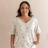 Smiling woman modeling the Women's Relaxed Fit V-Neck in Starry Icon with hand in white pants 