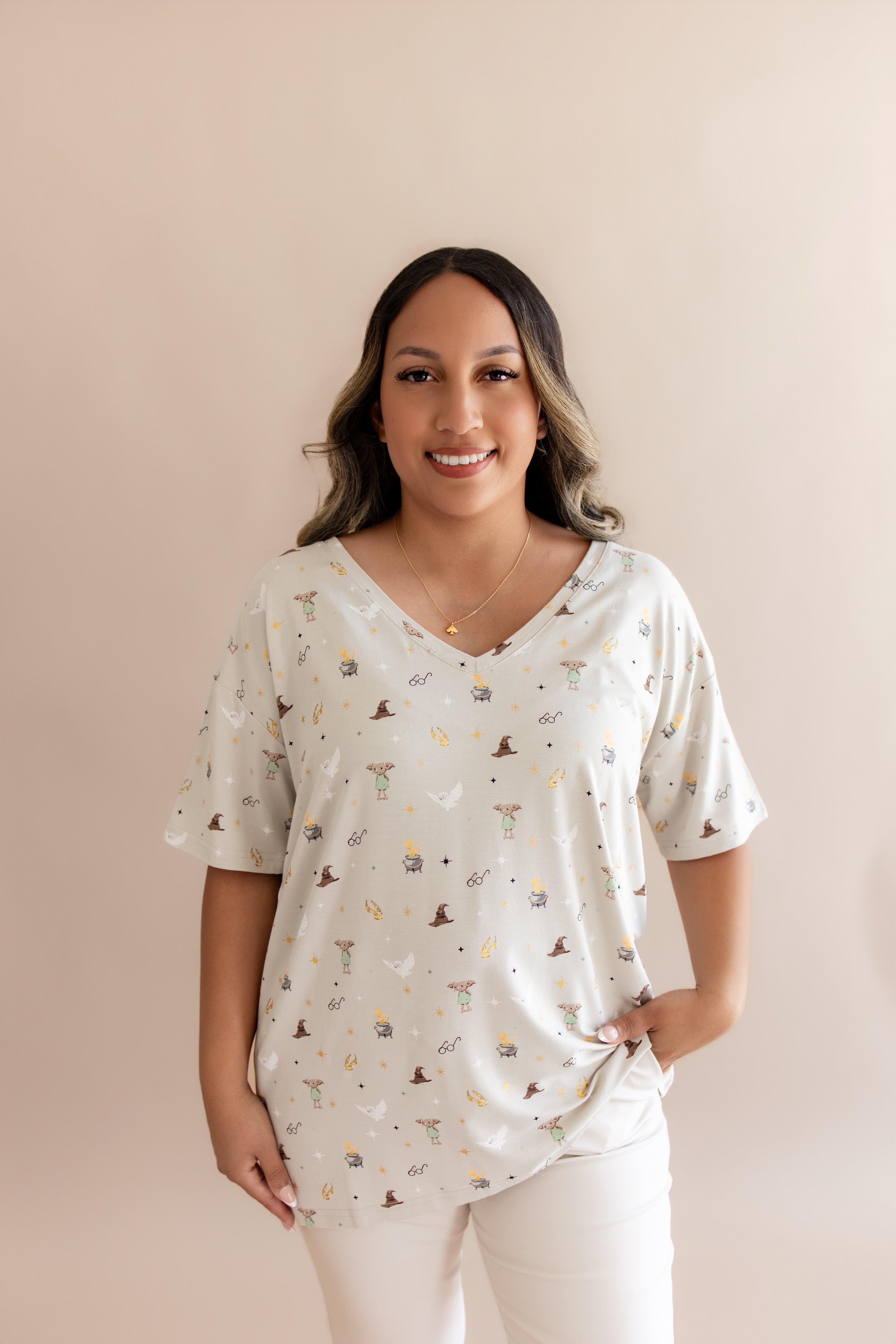 Smiling woman modeling the Women's Relaxed Fit V-Neck in Starry Icon with hand in white pants 
