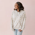 Woman wearing a beige hoodie with Harry Potter icons printed and blue jeans