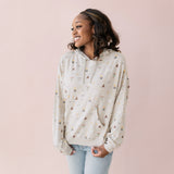 Woman wearing a beige hoodie with Harry Potter icons printed and blue jeans