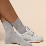 Gray crew socks worn with white sneakers on a beige background