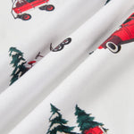 White fabric with a repeating print of red wagons, green pine trees, and a red sled, shown in a close-up folded view.