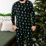 Smiling male model wearing the Men's Jogger Set in Twinkle Trees next to a Christmas tree and bed