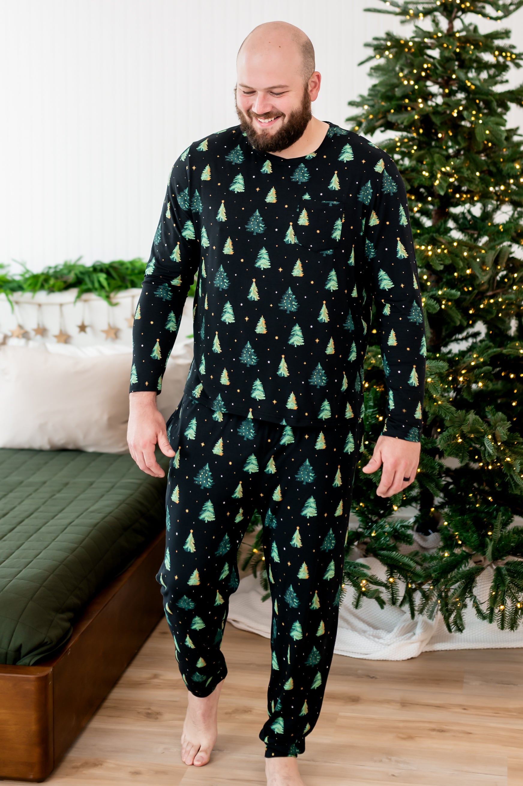 Made model looking downwards while wearing the Men's Jogger Set in Twinkle Trees next to a Christmas tree