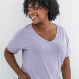 Model looking to the side with hand on hip and wearing the Kyte Women's V Neck in Taro paired with dark jeans