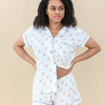 Model wearing Women’s Short Sleeve Pajama Set in Teddy Bear holding pajama top slightly up to show waistband of pajama short