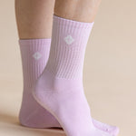A pair of light lavender ribbed crew socks worn on feet, shown against a solid beige background.