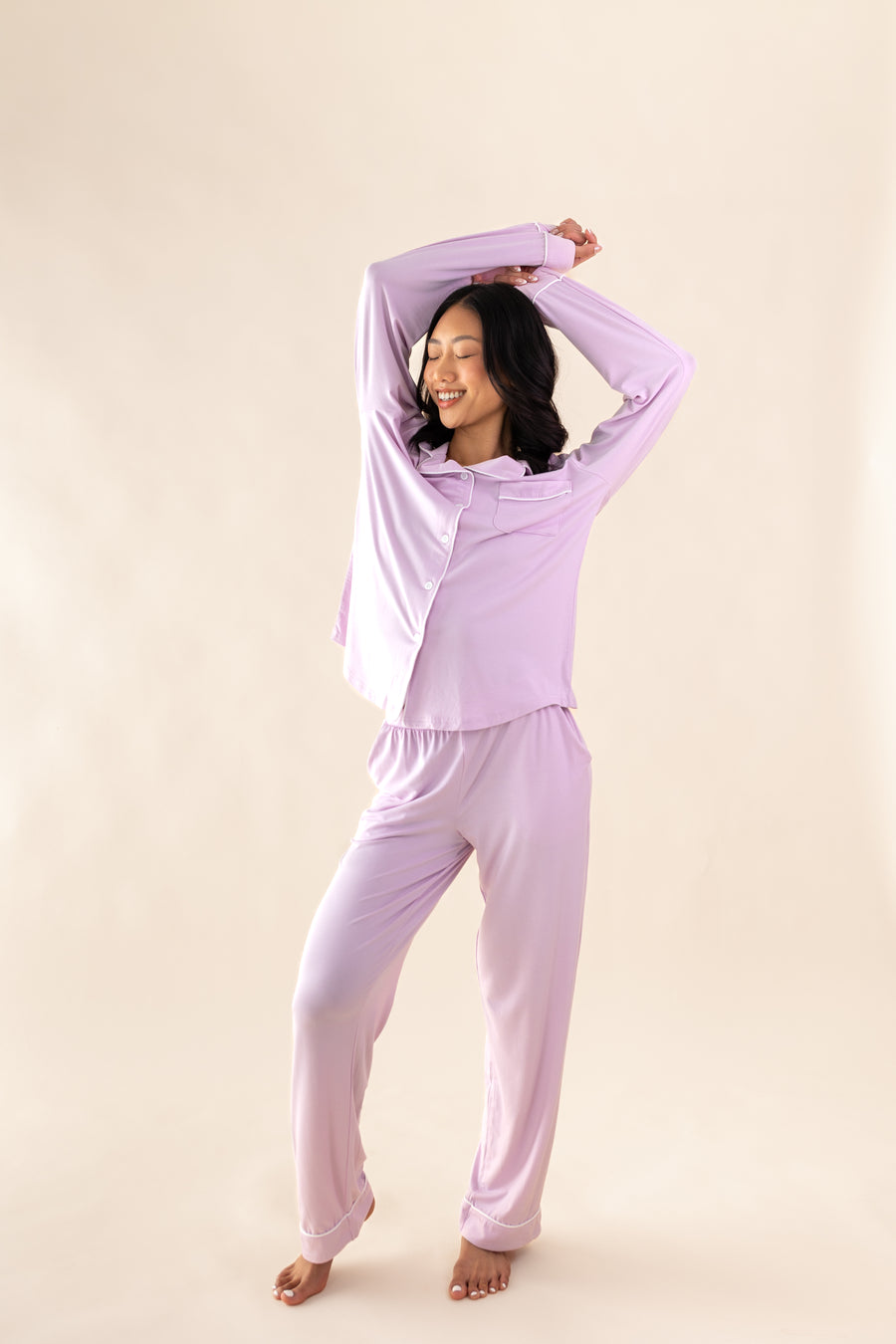 Smiling model with eyes closed wearing the Bamboo Long-Sleeved Women's Pajama Set in Thistle with arms above her head