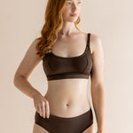 Woman modeling the Women's Pumping Bra in Toffee paired with matching underwear in front of a beige back ground 


