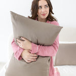 Female holding a pillow with the Bamboo Sateen Pillowcase in Truffle on it