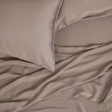 Close up of the Bamboo Sateen Pillowcase Set in Truffle with matching bed sheets on a bed