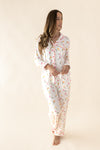 Woman wearing a white pajama set with colorful floral patterns on a beige background  ::: Model is 5'11" wearing size S ///