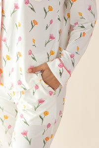 Floral-patterned pajama set with a hand adjusting the sleeve on a beige background
