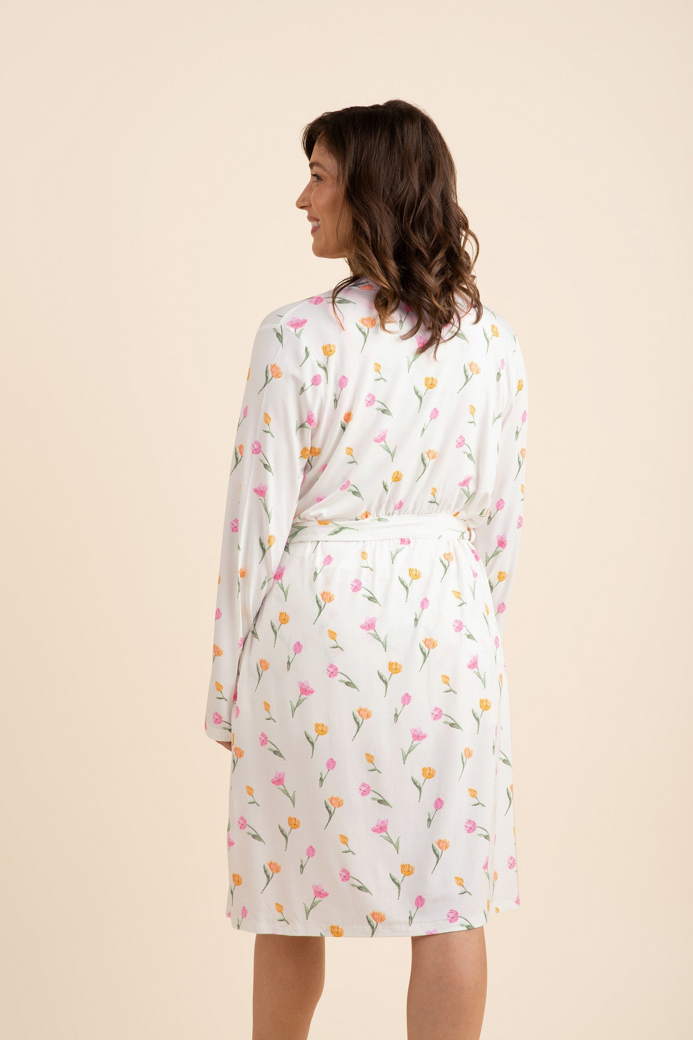 The back of the Women's Lounge Robe in Tulip shown on a model standing in front of a light taupe background