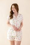 Female modeling the Women's Short Sleeve Pajama Set in Tulip standing in front of a light cream background ::: Model is 5'7" wearing size M ///