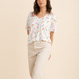 Female posing in front of a light beige background wearing the Women's Relaxed Fit V-Neck in Tulip with cream pants