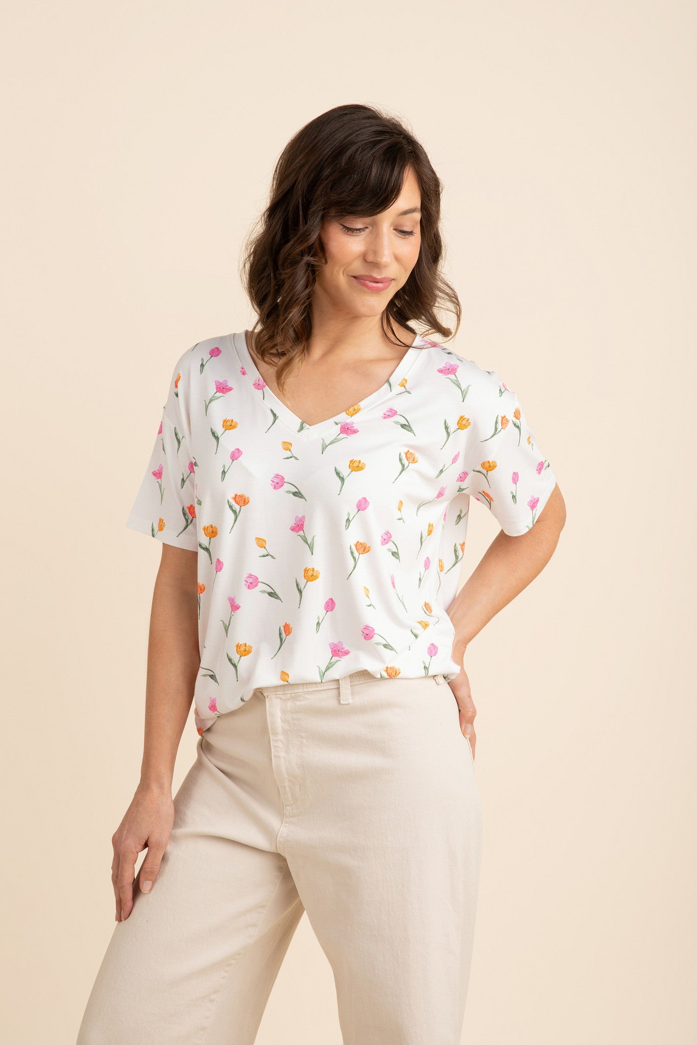 Female model wearing the Women's Relaxed Fit V-Neck in Tulip paired with light beige pants
