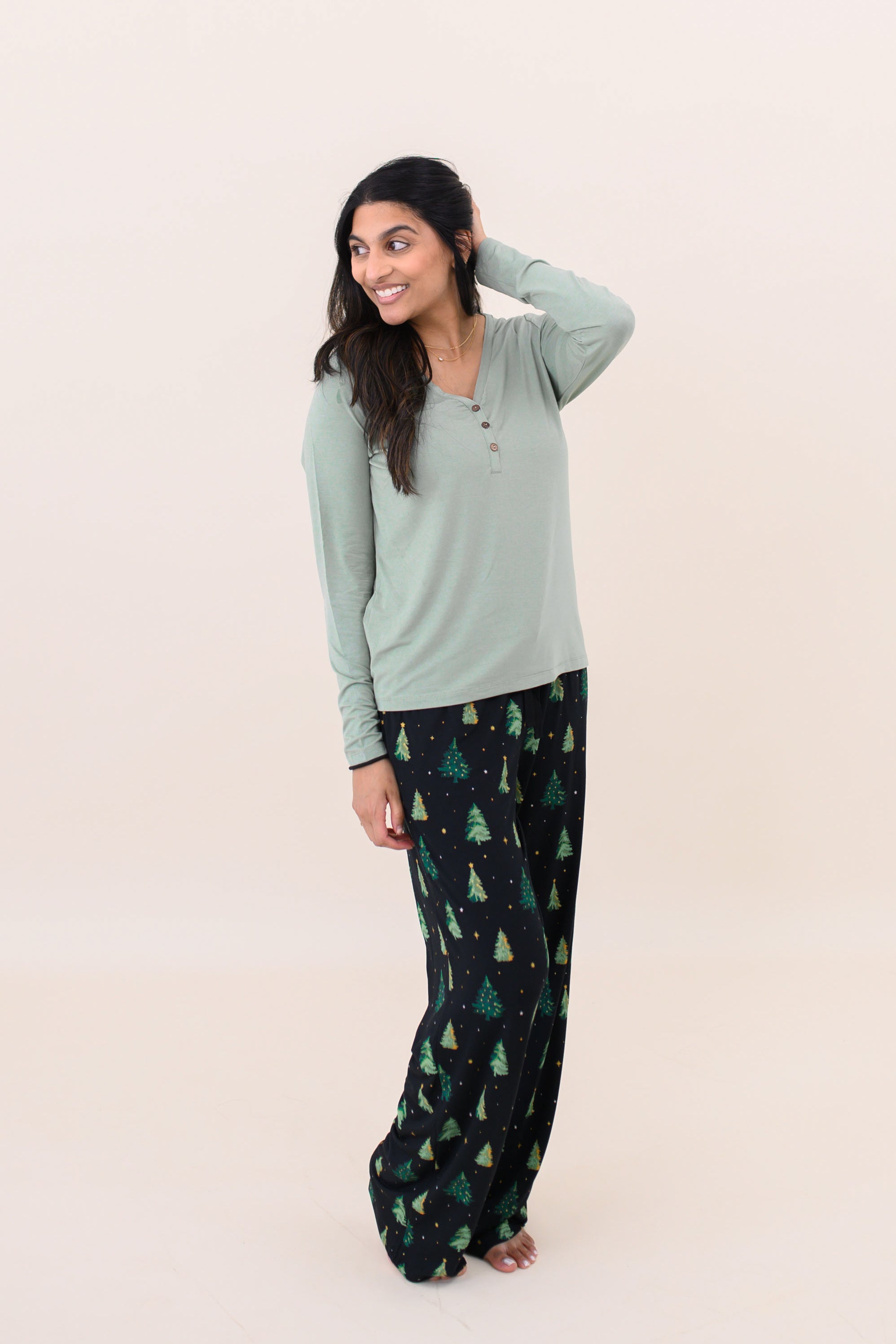 Model looking to the side with one hand on her head and wearing the Kyte Women's Lounge Pants in Twinkle Tree