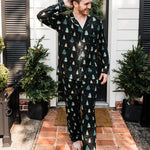 Model standing in front of a black door wearing the Men's Long Sleeve Pajama Set in Twinkle Tree