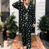 Model standing in front of a black door wearing the Men's Long Sleeve Pajama Set in Twinkle Tree