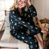 Model sitting partially curled up in a chair while wearing the Women's Long Sleeve Pajama Set in Twinkle Tree