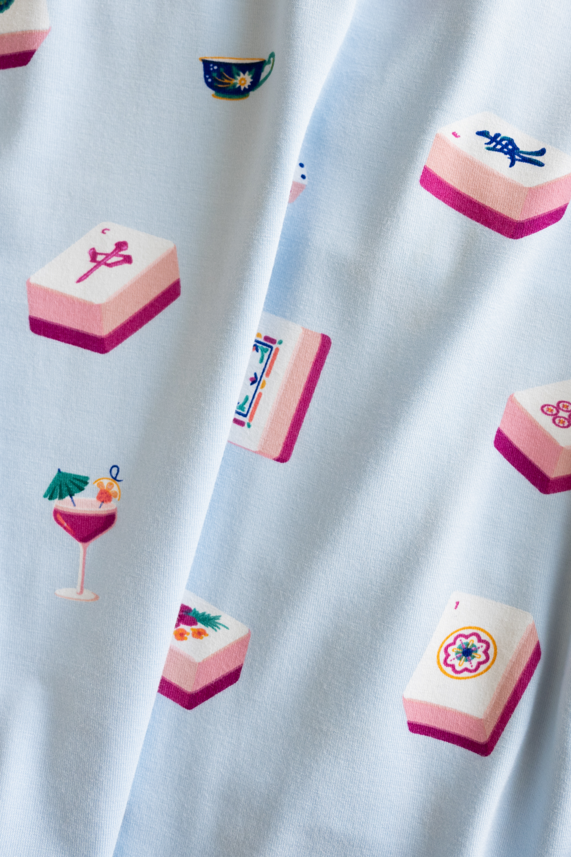 close up of fabric in light blue color with a pattern of pink mahjong