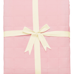 Pink quilted blanket folded and tied with ribbon