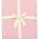 Pink quilted blanket folded and tied with ribbon
